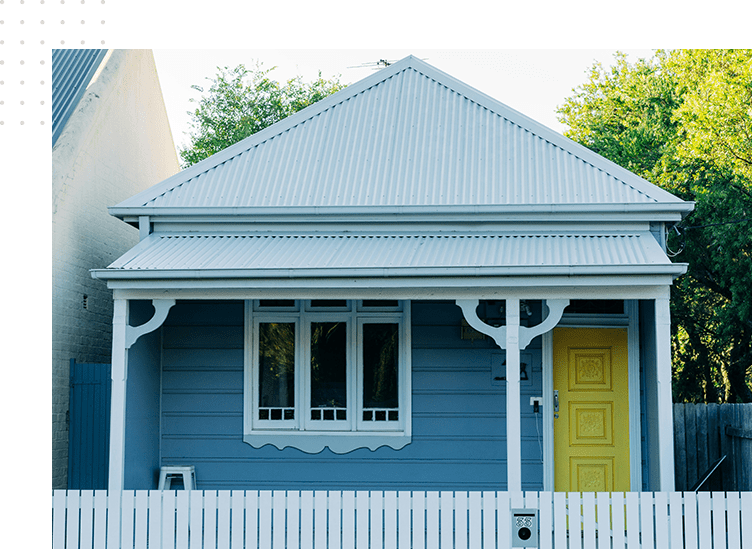 A blue house with white picket fence and yellow door.