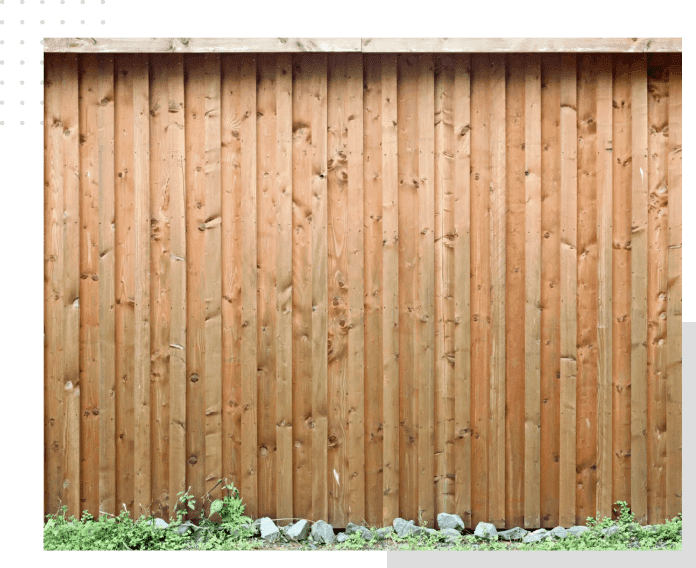 A wooden fence with grass growing in front of it.