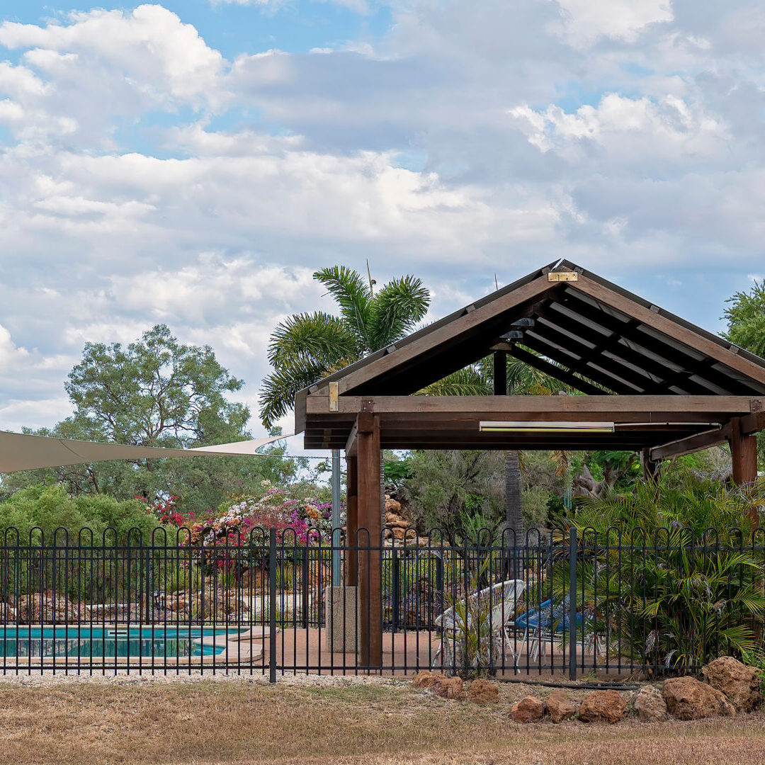 A wooden structure with a pool in the background.