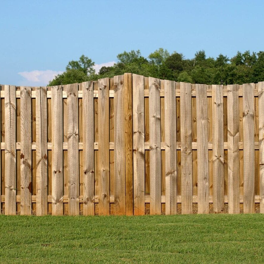 A wooden fence with grass in the foreground.