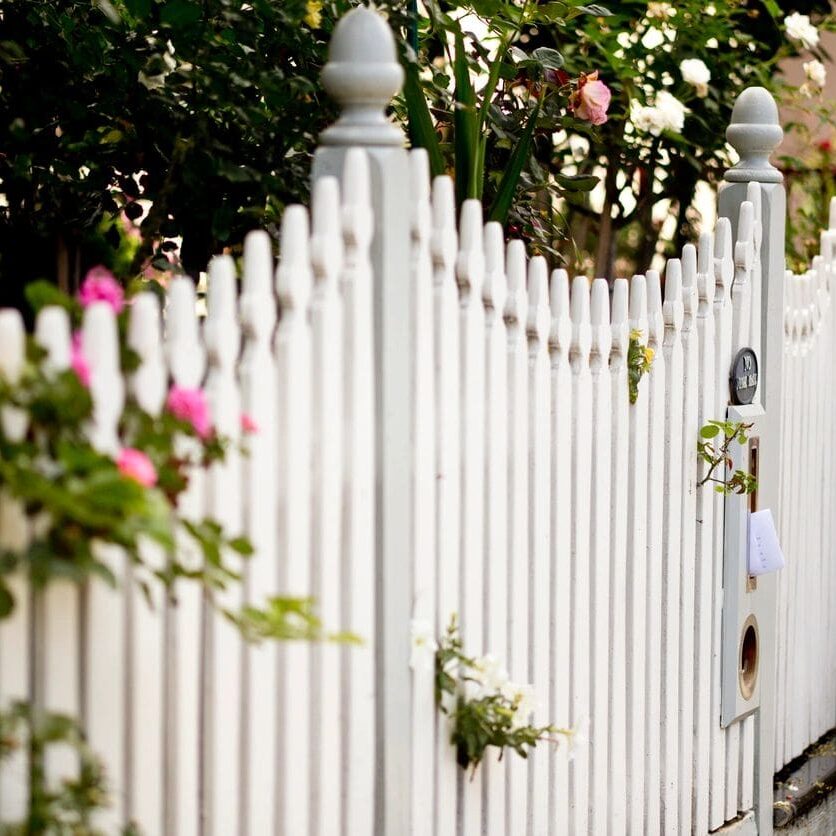 A white fence with flowers growing on it.